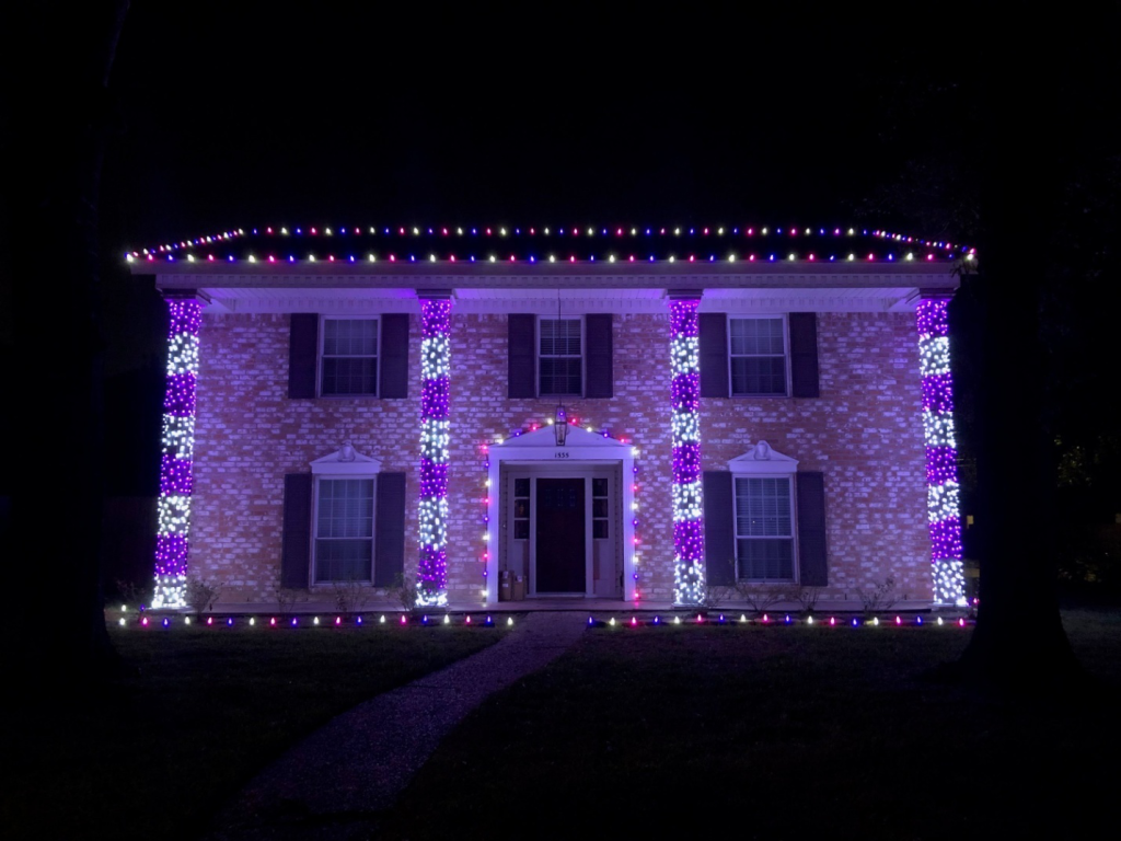 A charming house adorned with pink, purple, and white lights