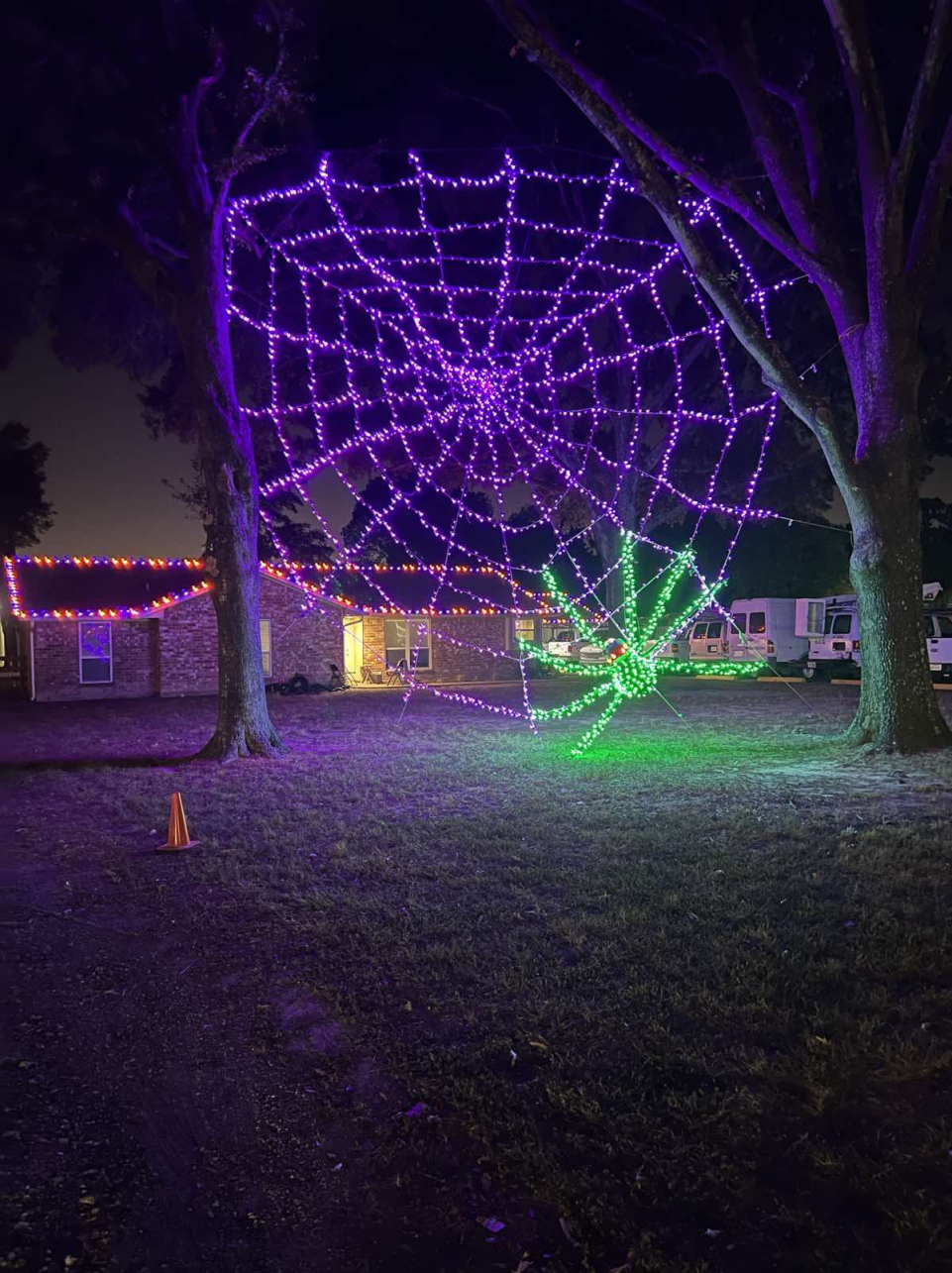 Halloween lighting display featuring a glowing spider on a spider web